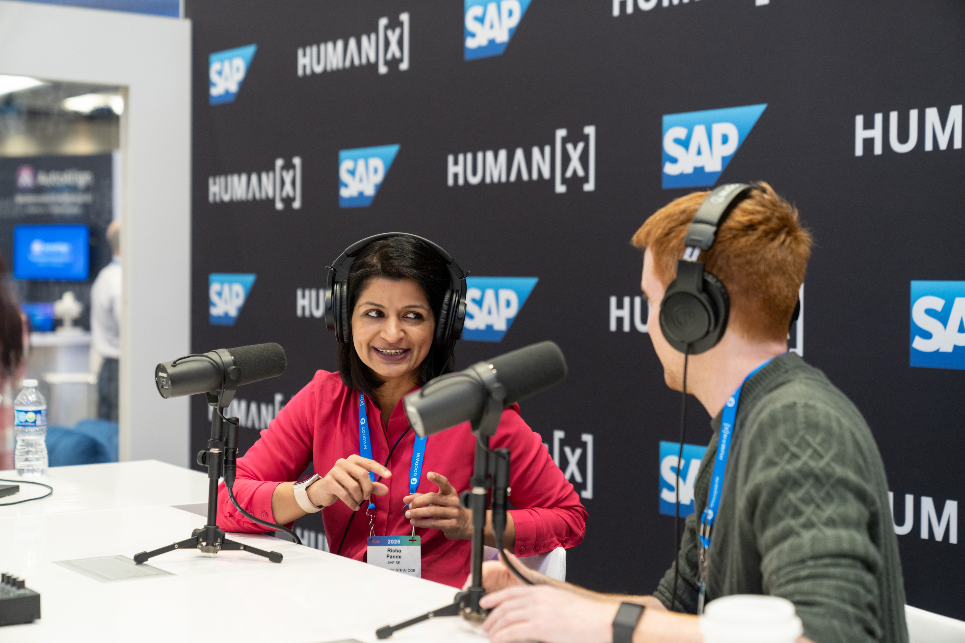 two podcasters are in discussion in the podcast booth on the show floor at HumanX 2025