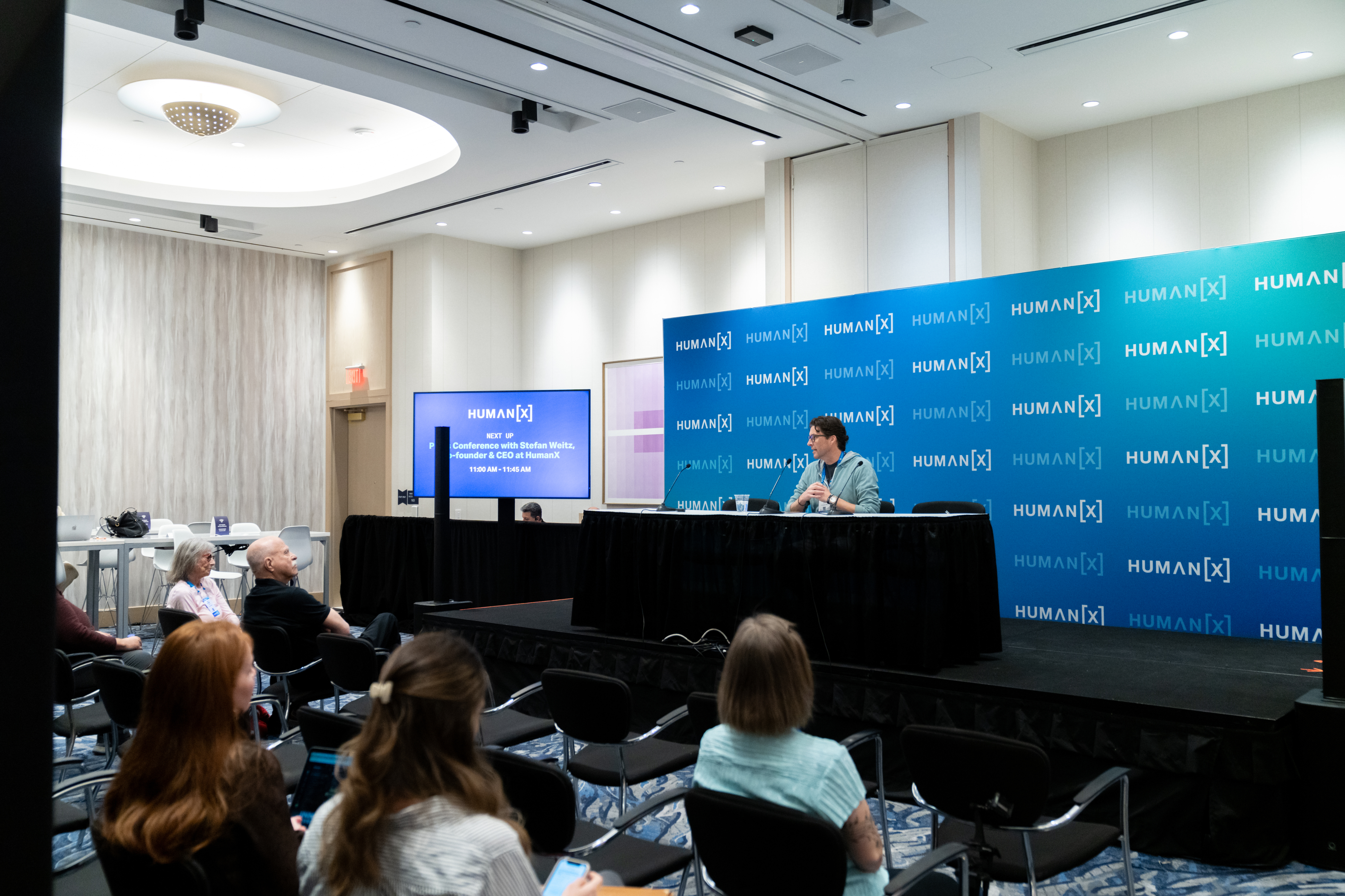 a view of the media lounge at humanx 2025 with a speaker giving a press conference