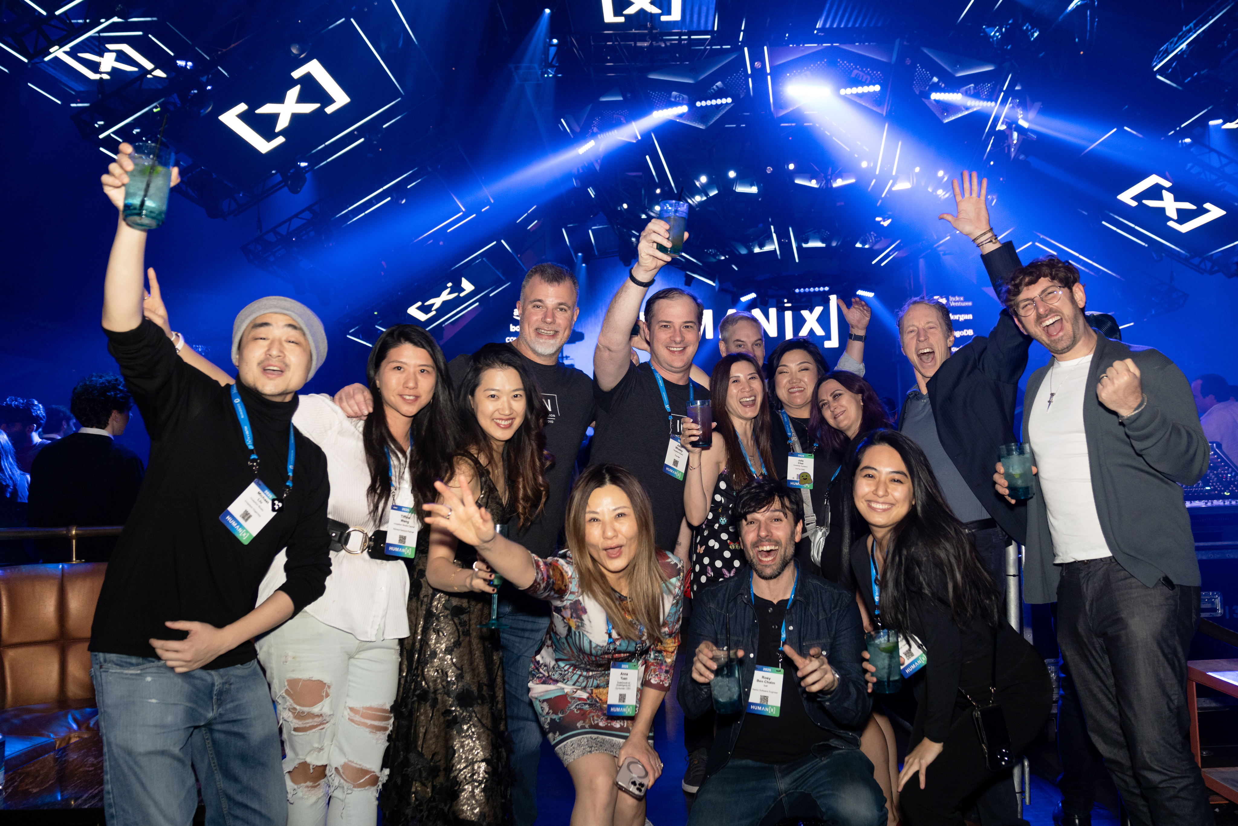 a group of people at the humanx 2025 after party pose cheerily for the camera with the nightclub in the background